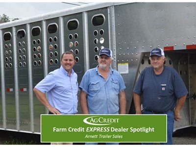 Three men standing in front of a horse trailer 