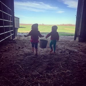 two children carrying a bucket out of a barn
